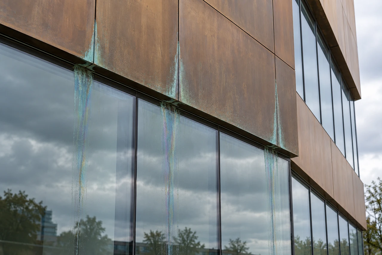 Bronze-clad building with iridescent runoff on glass
