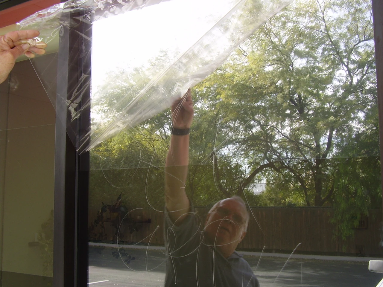 Applied film being removed from glass; this photo does not identify its safety or security performance.